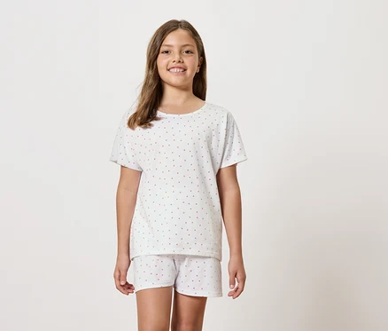 Une fille porte un pyjama blanc à manches courtes et un short.