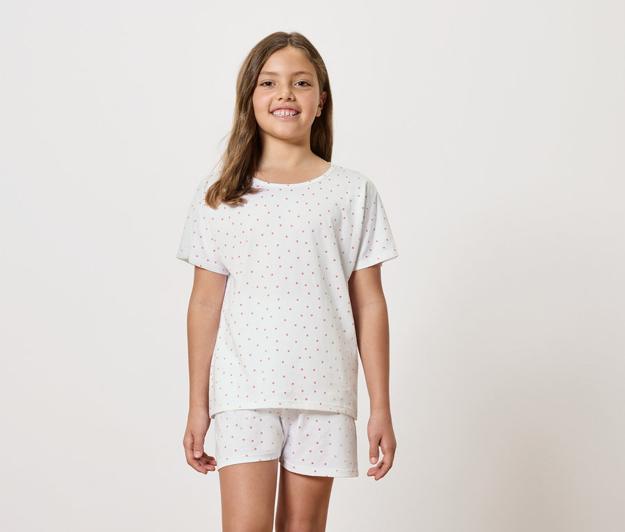 Une fille porte un pyjama blanc à manches courtes et un short.