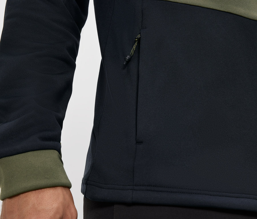 Gros plan sur une veste noire et vert olive avec fermeture éclair et poche zippée.