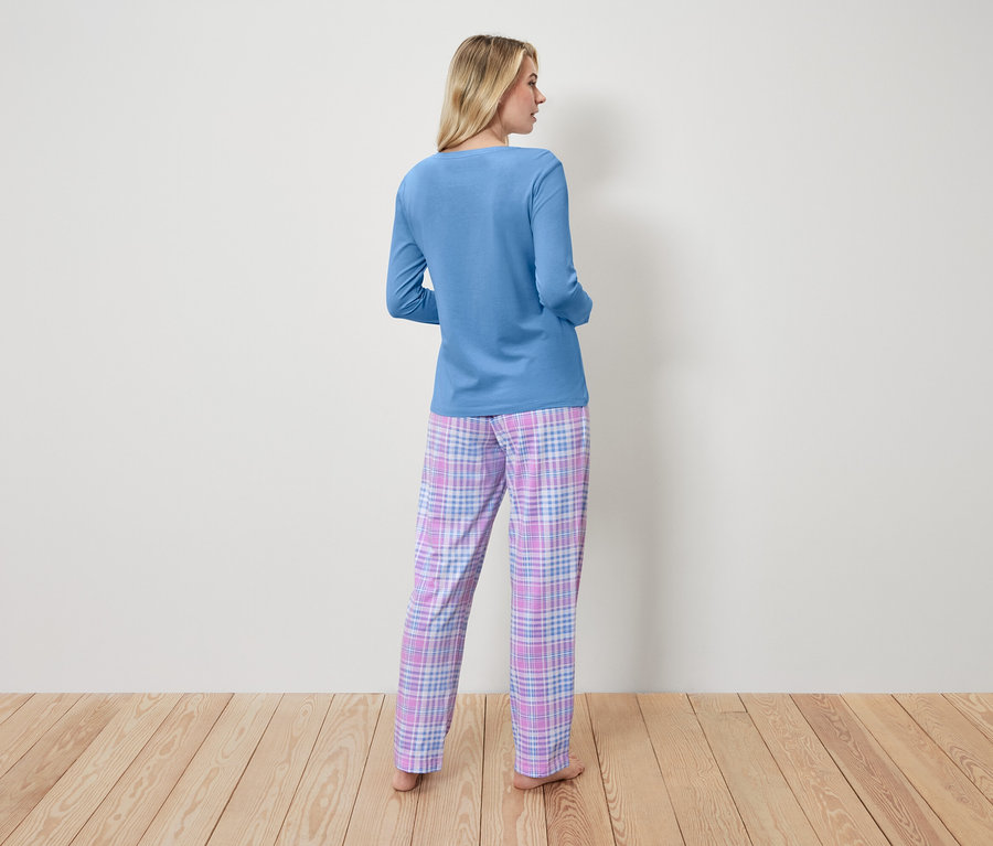 Une femme en haut de pyjama bleu et pantalon à carreaux, dos à la caméra.