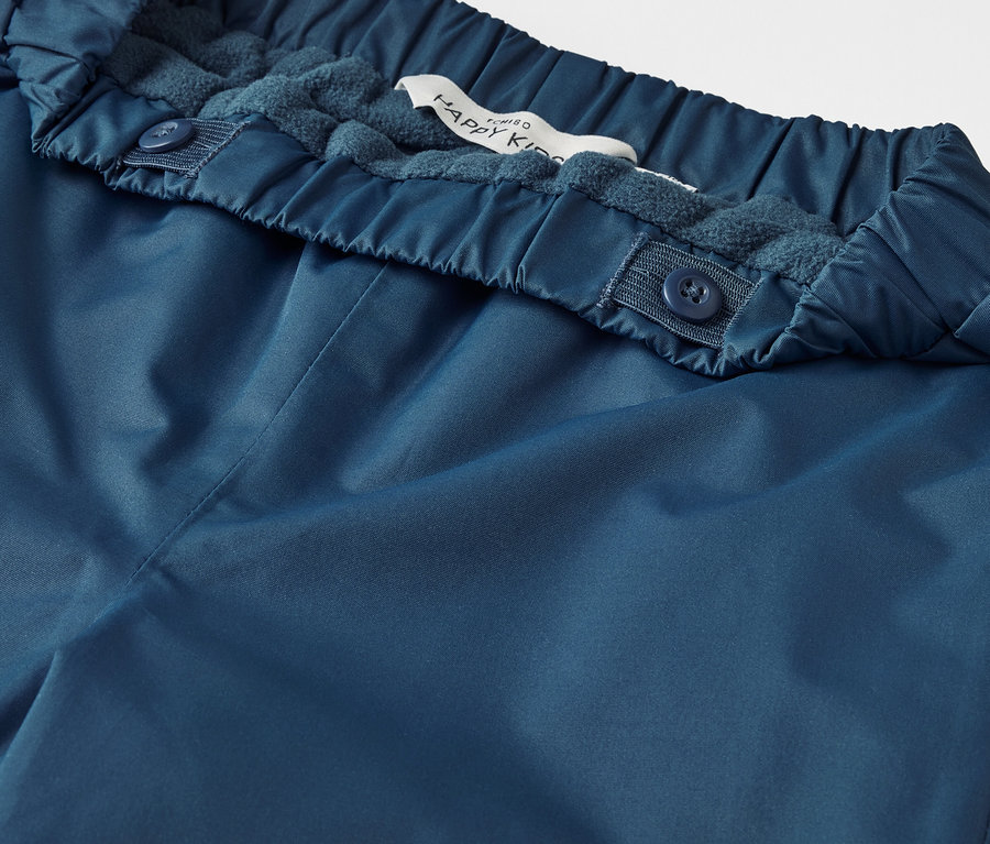 Gros plan sur un pantalon de pluie thermique bleu pour enfant.