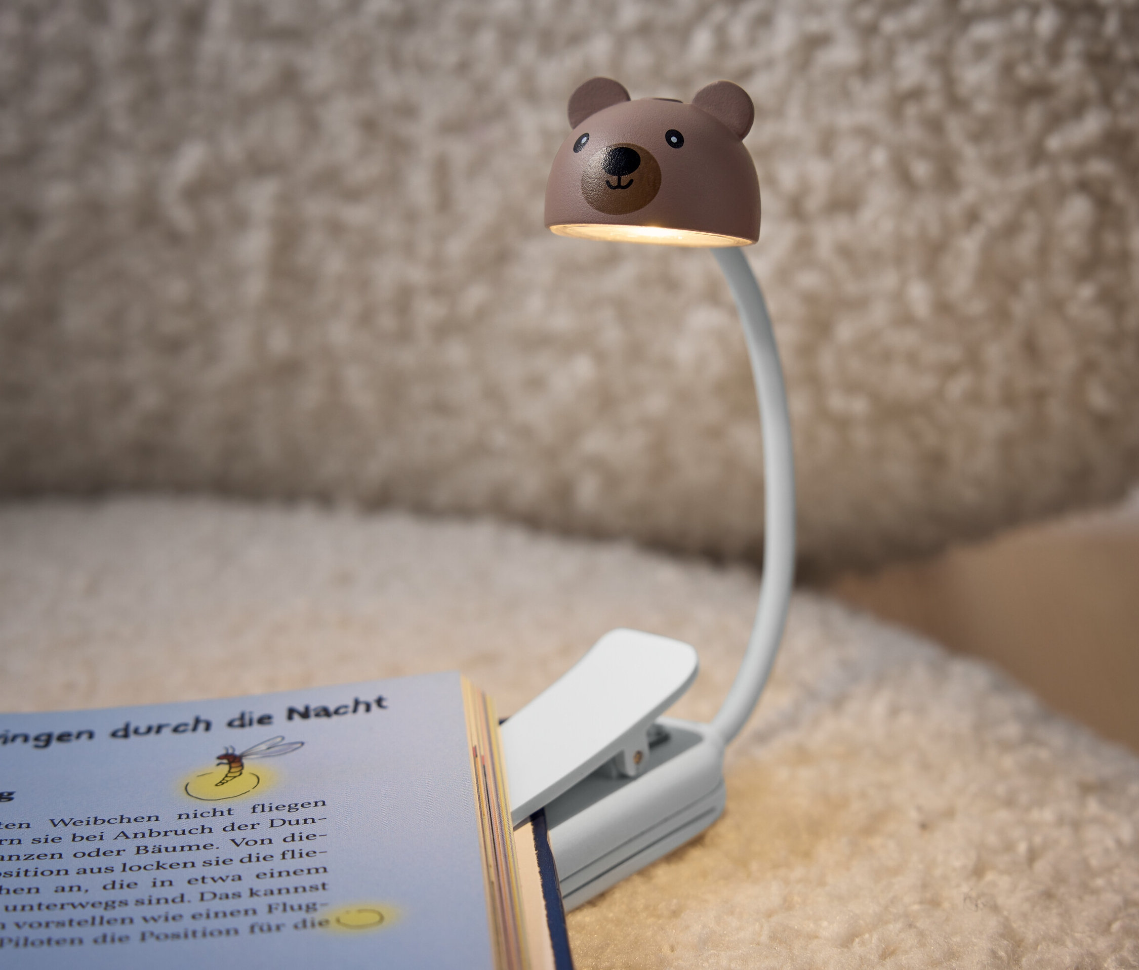 Une lampe de lecture en forme d'ours attachée à un livre.