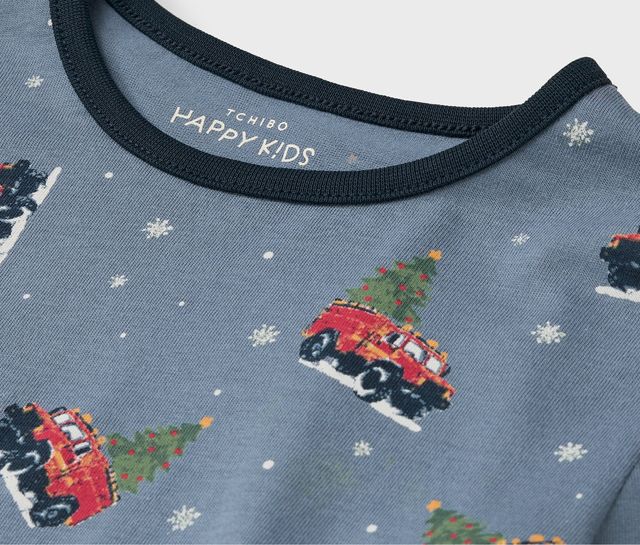 Détail d'un t-shirt bleu avec des voitures imprimées avec des arbres de Noël et des flocons de neige.