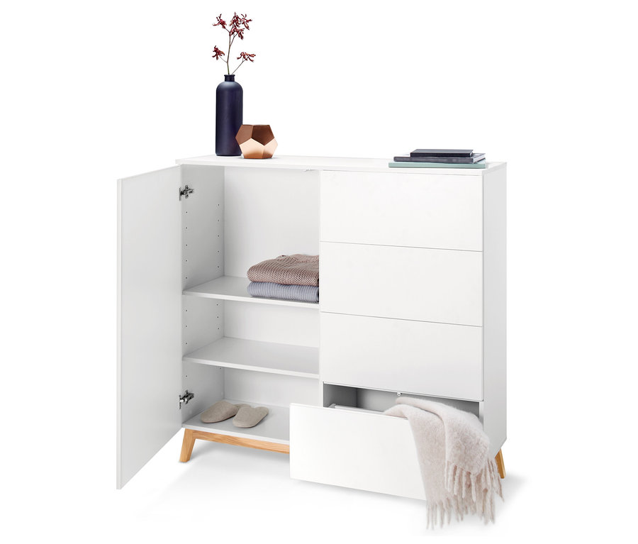 Commode blanche ouverte avec étagères, vêtements, chaussons et tiroirs.