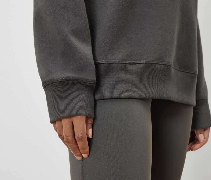 Gros plan d'une femme portant un pull et un legging gris.