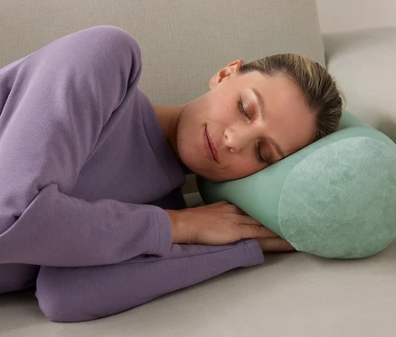 Femme dormant sur un canapé avec un coussin de relaxation.