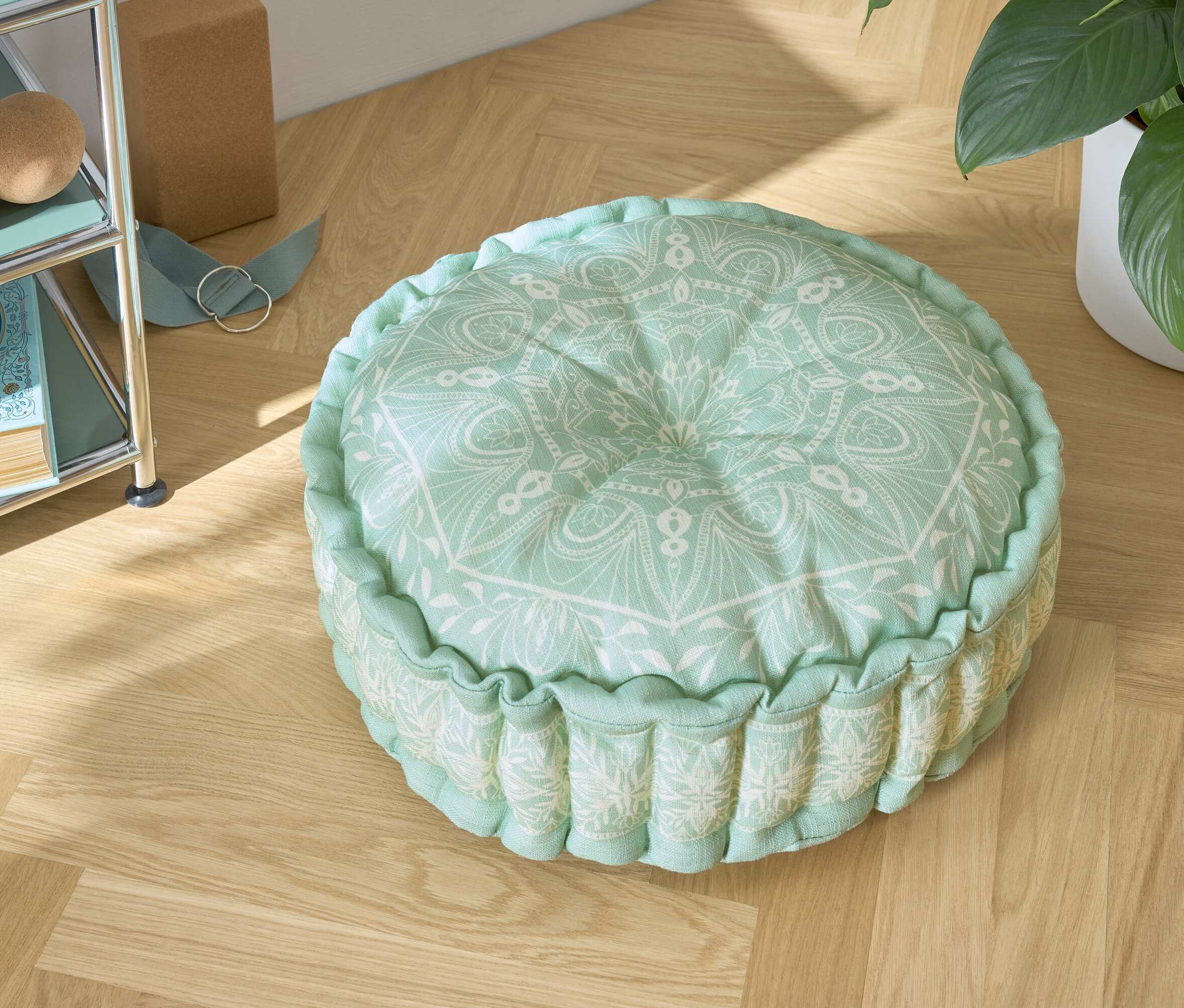 Un coussin de sol vert avec un motif blanc sur un plancher en bois.