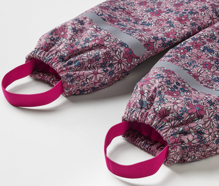 Détail d'un pantalon de pluie thermique pour enfant avec un motif floral et des éléments réfléchissants.