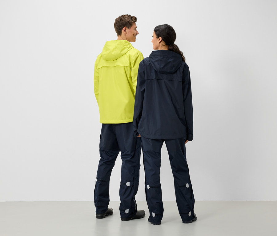 Un homme et une femme se tiennent dos à dos et portent des vestes et des pantalons de pluie.