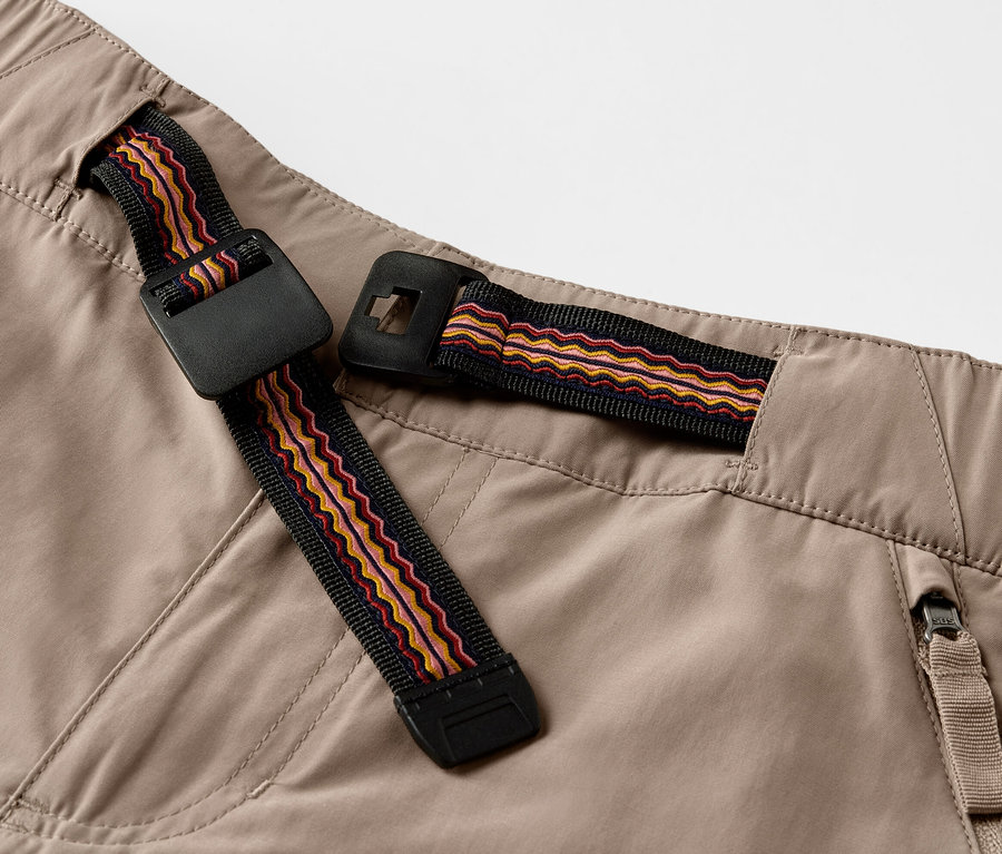Détail d'un pantalon d'extérieur avec protection anti-moustiques et ceinture décorative.