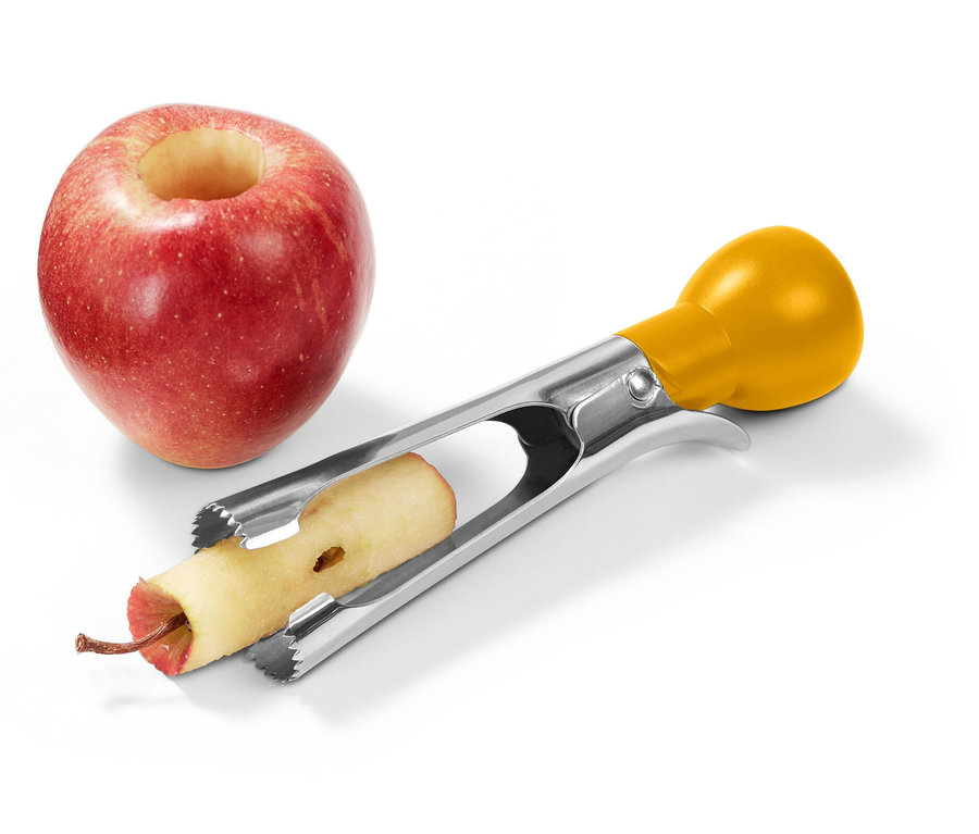 Une pomme rouge avec un centre évidé se trouve à côté d'un vide-pomme en acier inoxydable avec une poignée jaune, qui retire le cœur d'une deuxième pomme.