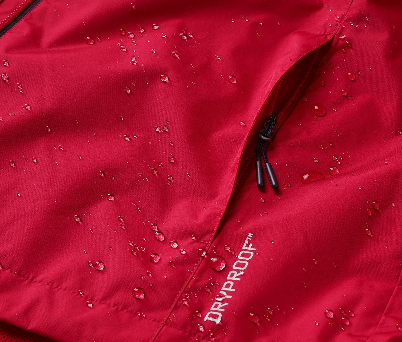 Gros plan sur une veste de pluie rouge avec des gouttes d'eau et une poche.