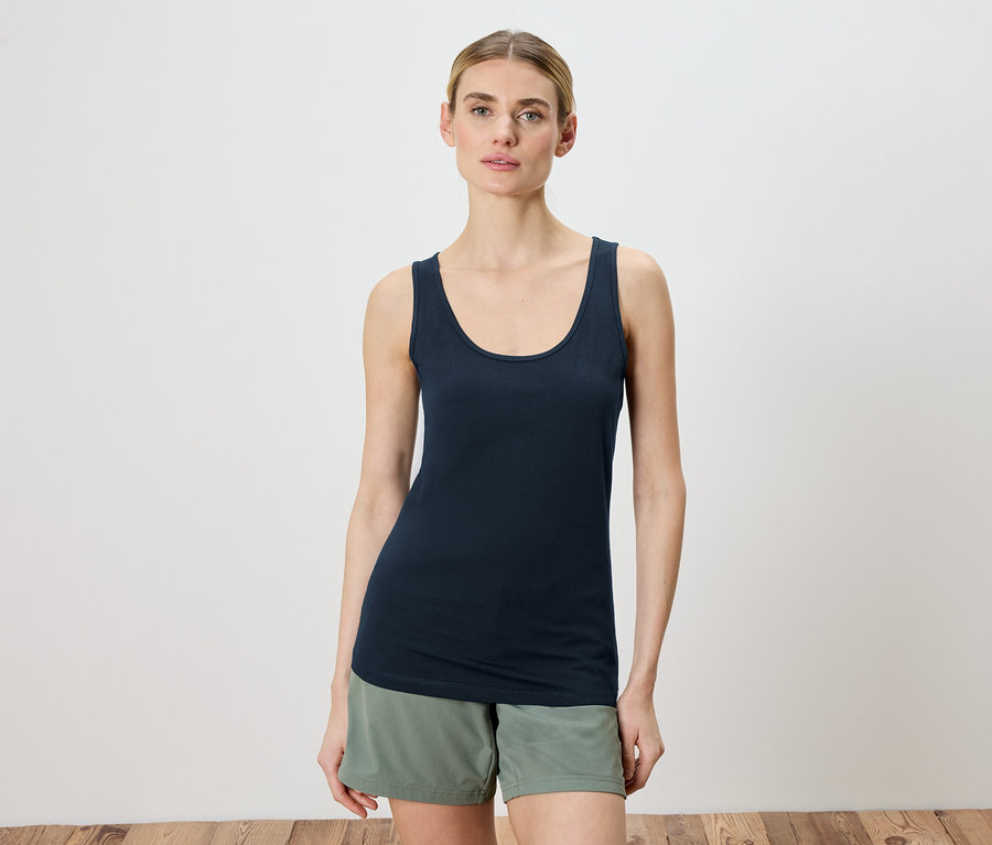 Femme portant un débardeur bleu marine et un short vert.