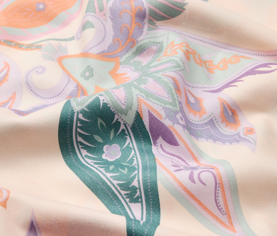 Gros plan d'un tissu à motif floral dans les tons vert, violet et orange.