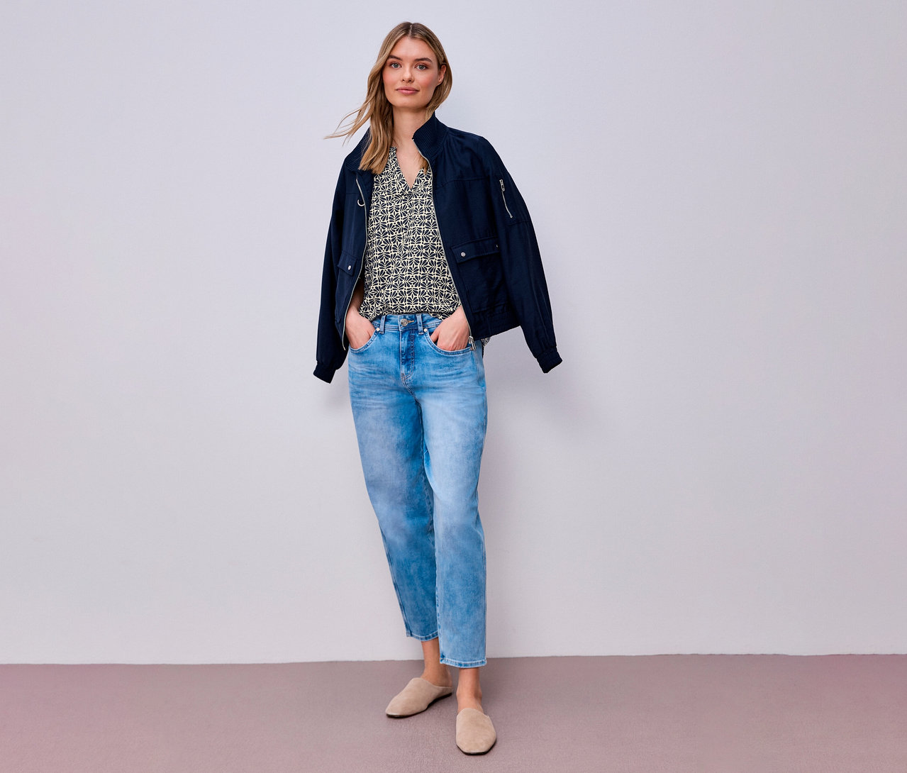 Femme portant un jean et une blouse en maille Street One, avec une veste par-dessus. Elle a les mains dans les poches de son pantalon.