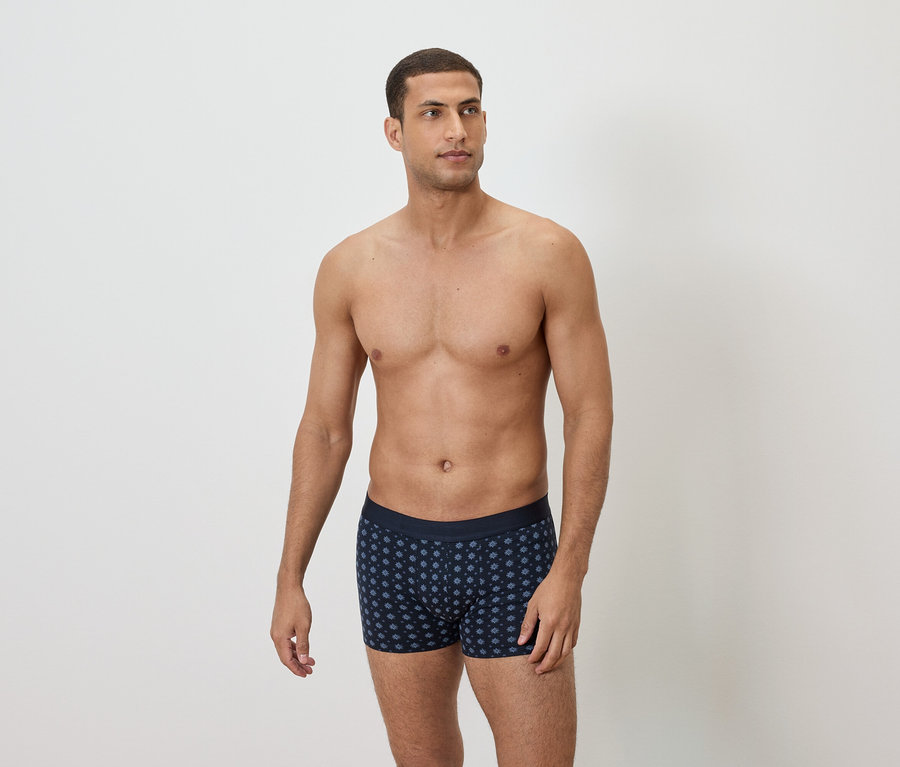 Homme torse nu portant un boxer bleu marine à pois.