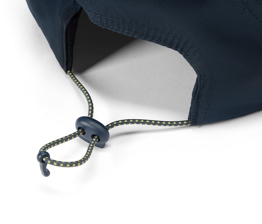 Gros plan d'une casquette bleu marine avec un cordon de serrage réglable à pois jaunes.