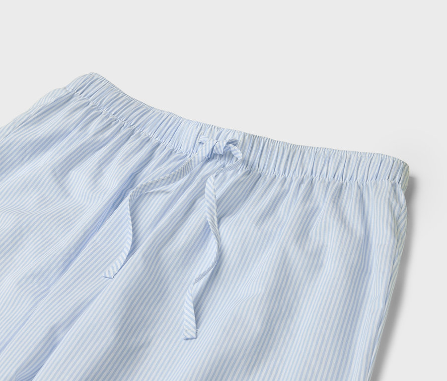 Gros plan sur un pantalon de pyjama rayé bleu clair et blanc avec cordon de serrage.