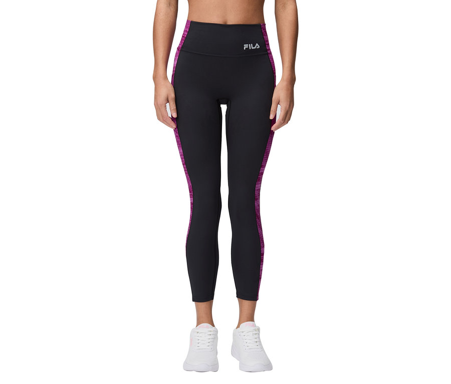 Une femme porte un legging Fila noir avec des rayures violettes et des baskets blanches.