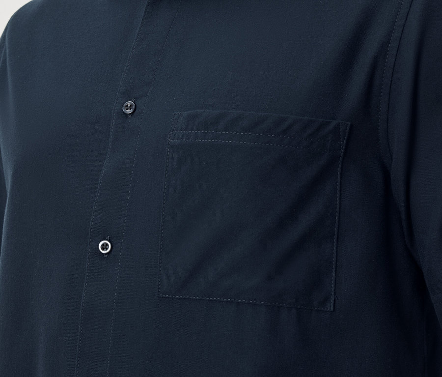 Gros plan d'une chemise à manches courtes bleu marine avec une patte de boutonnage et une poche de poitrine plaquée.