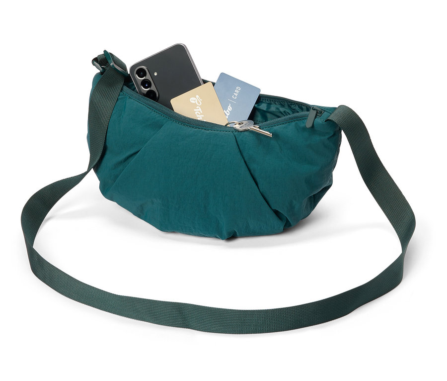 Sac bandoulière vert avec téléphone, cartes et clés.