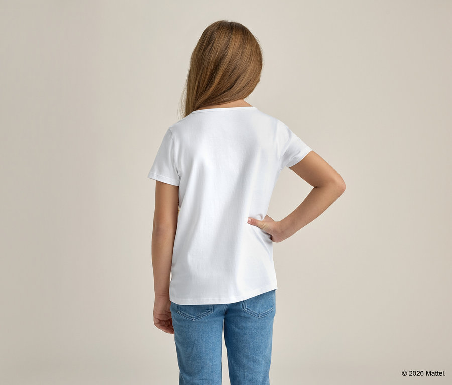 Une fille aux cheveux blonds, vue de dos, porte un t-shirt blanc et un jean bleu, la main sur la hanche.