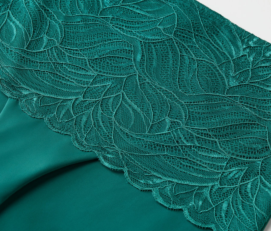 Gros plan d'un tissu vert émeraude avec de la dentelle florale.