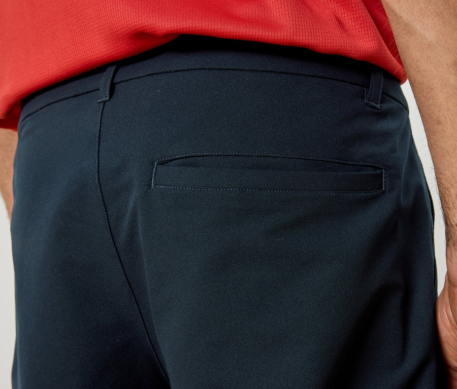 Gros plan sur l'arrière d'un pantalon bleu marine avec une poche arrière, porté par une personne portant un haut rouge.