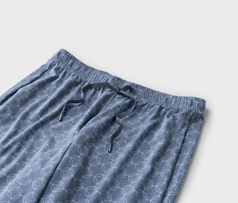Gros plan d'un pantalon bleu avec taille élastique, cordon de serrage et motif de cercles blancs.