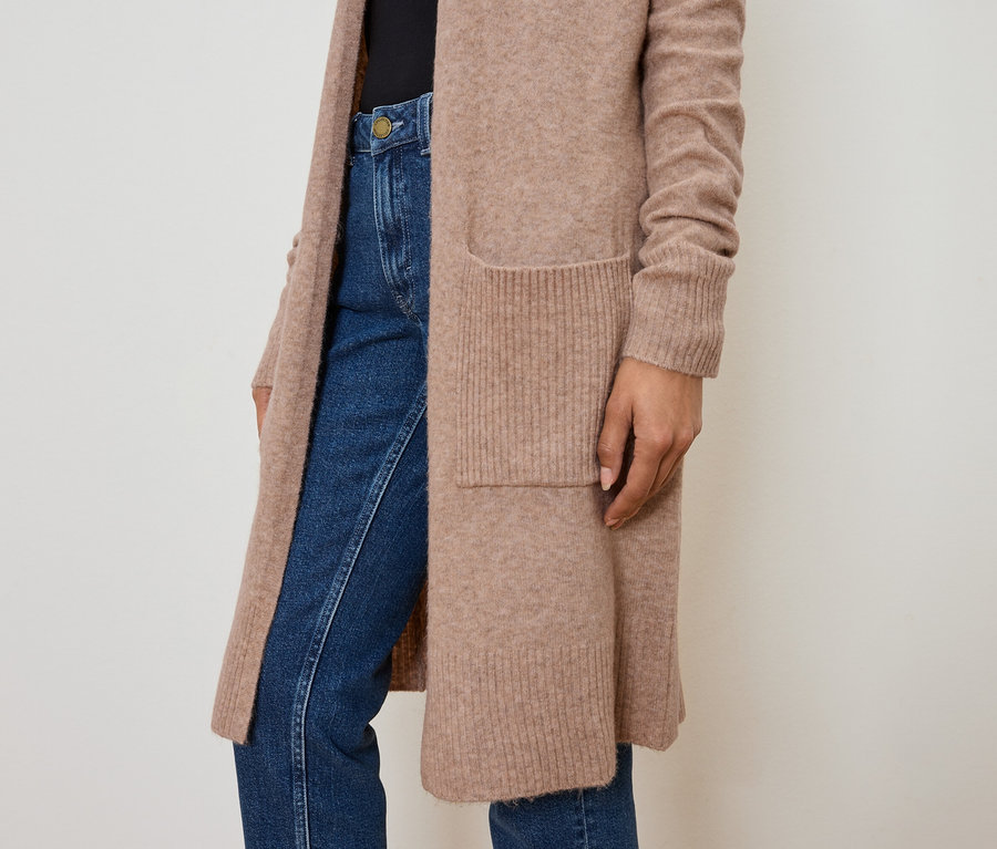 Gros plan d'une femme portant un long cardigan marron clair avec des poches et un jean.