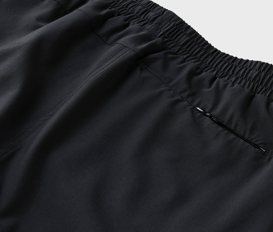 Gros plan sur l'arrière d'un pantalon noir avec une taille élastique et une poche zippée.