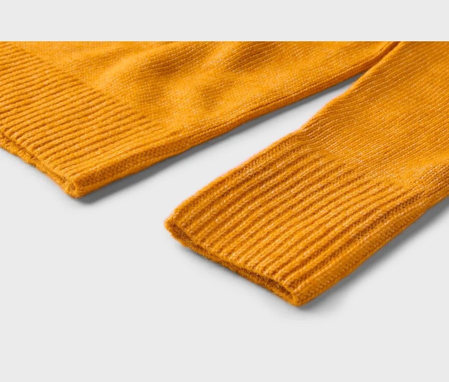 Gros plan d'un tissu en maille jaune vif, montrant un bord côtelé et un poignet de manche côtelé.