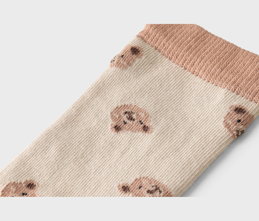 Gros plan d'une chaussette marron clair avec un motif d'ours et une bordure côtelée.