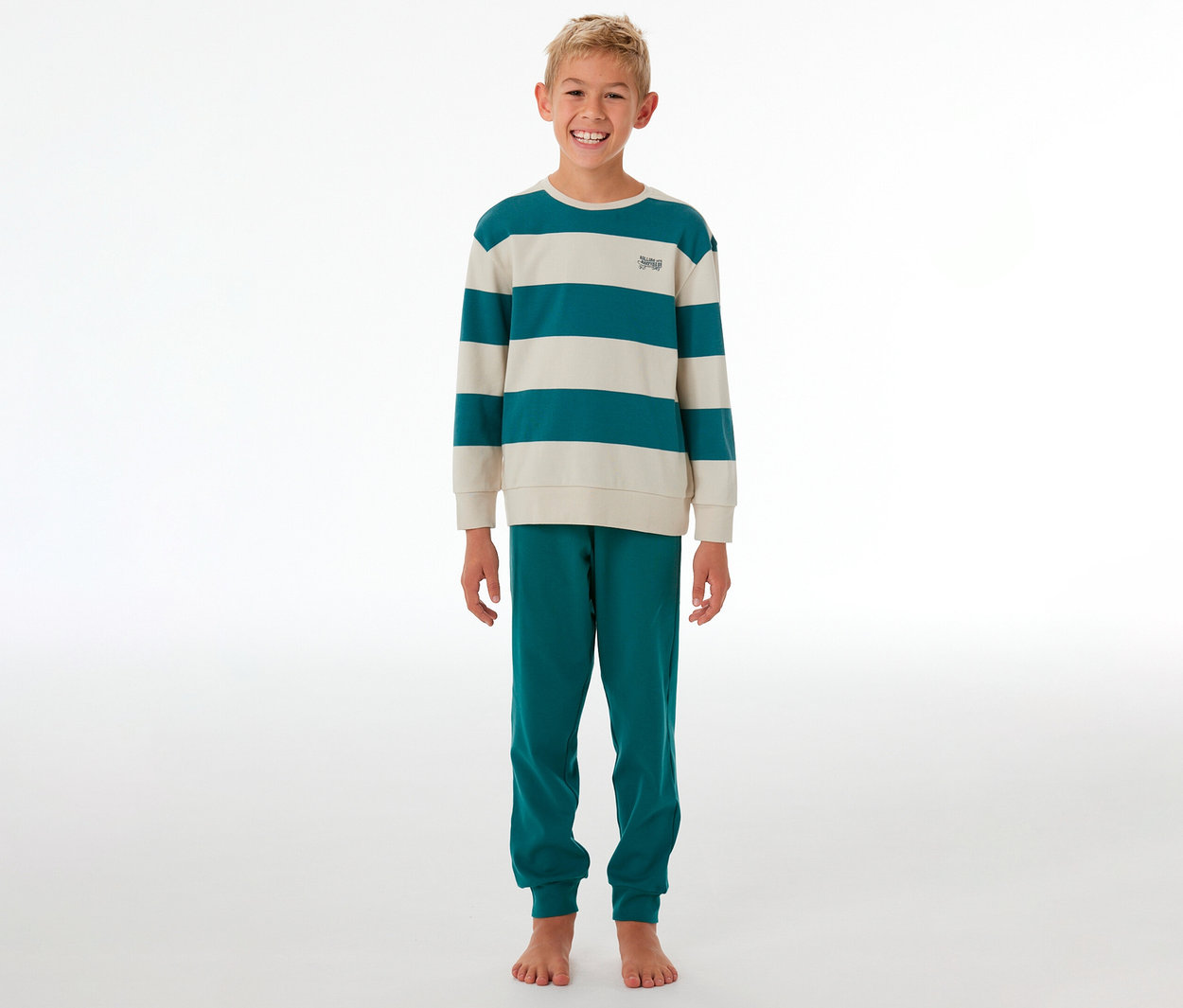 Garçon souriant debout dans un pyjama rayé turquoise et crème.