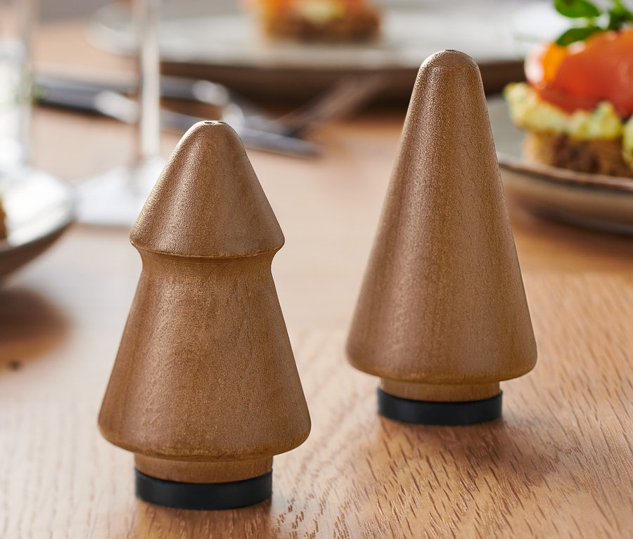 Deux salières et poivrières en bois en forme d'arbre sur une table avec des amuse-gueules au saumon.