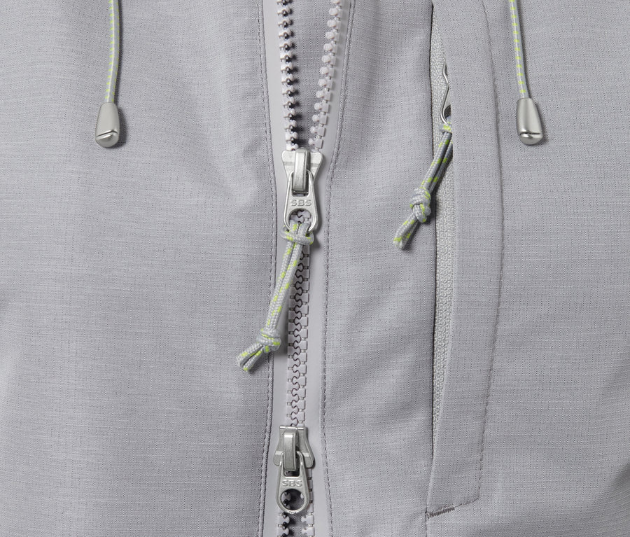 Gros plan sur une veste d'extérieur technique grise avec fermeture éclair et poche.