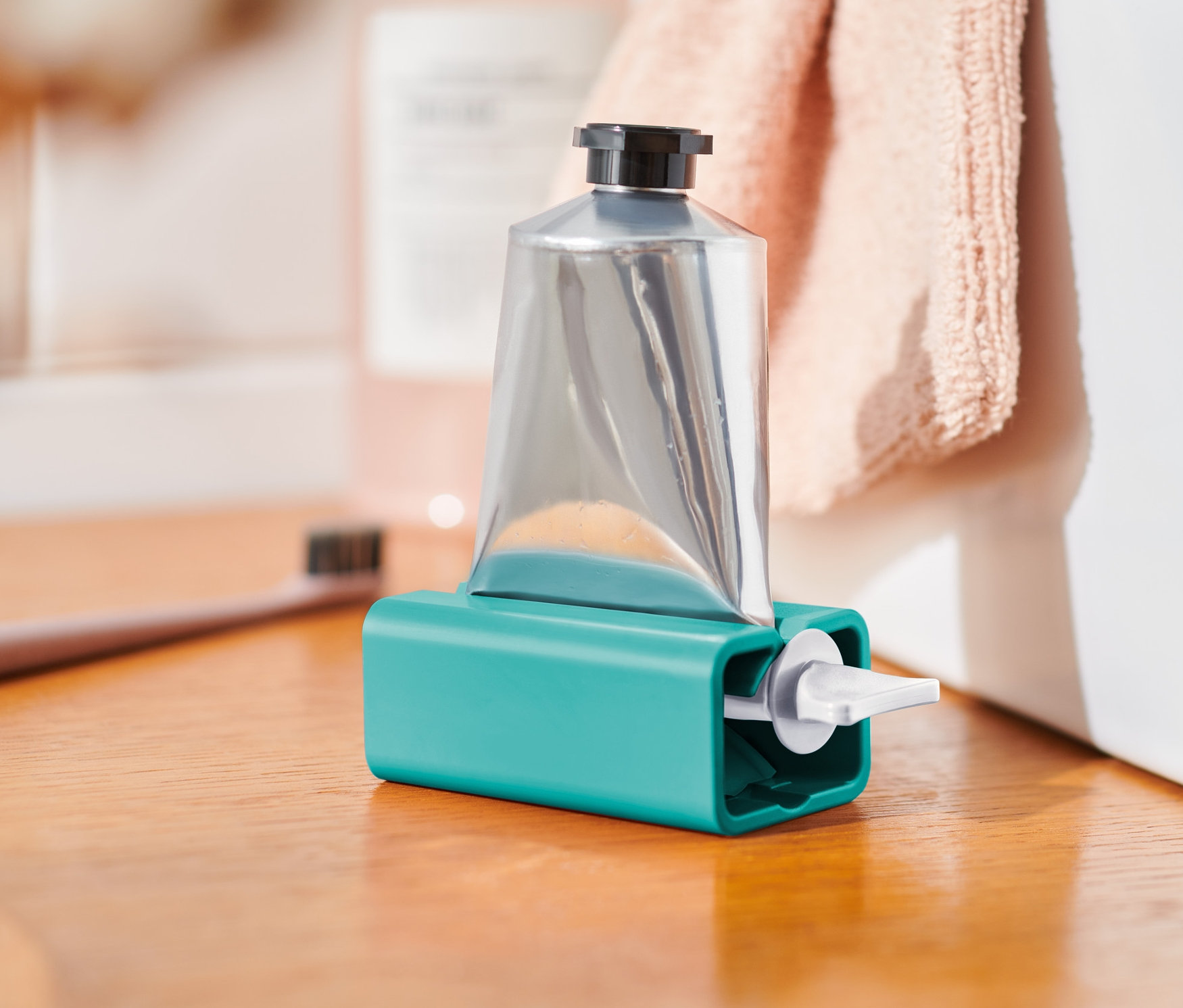 Tube argentée dans un presse-tube turquoise sur une étagère en bois.