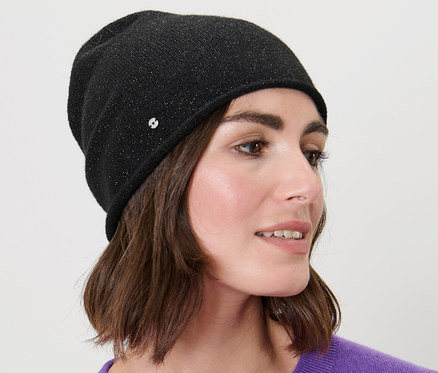 Femme aux cheveux bruns portant un beanie en maille fine scintillant noir.