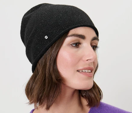 Femme aux cheveux bruns portant un beanie en maille fine scintillant noir.