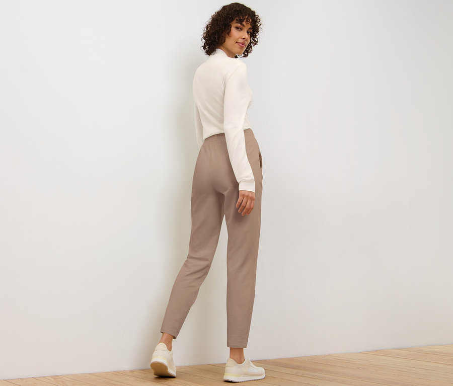 Femme regardant par-dessus son épaule portant un pantalon de jogging beige.