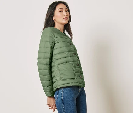Femme posant en veste matelassée verte.