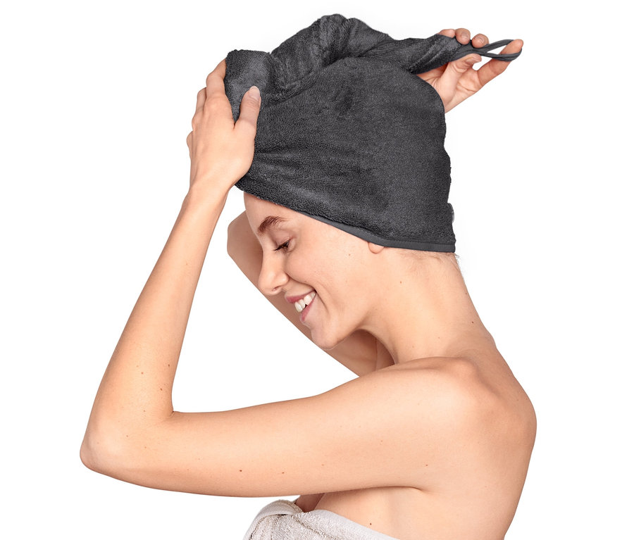 Femme mettant une serviette turban anthracite sur sa tête.