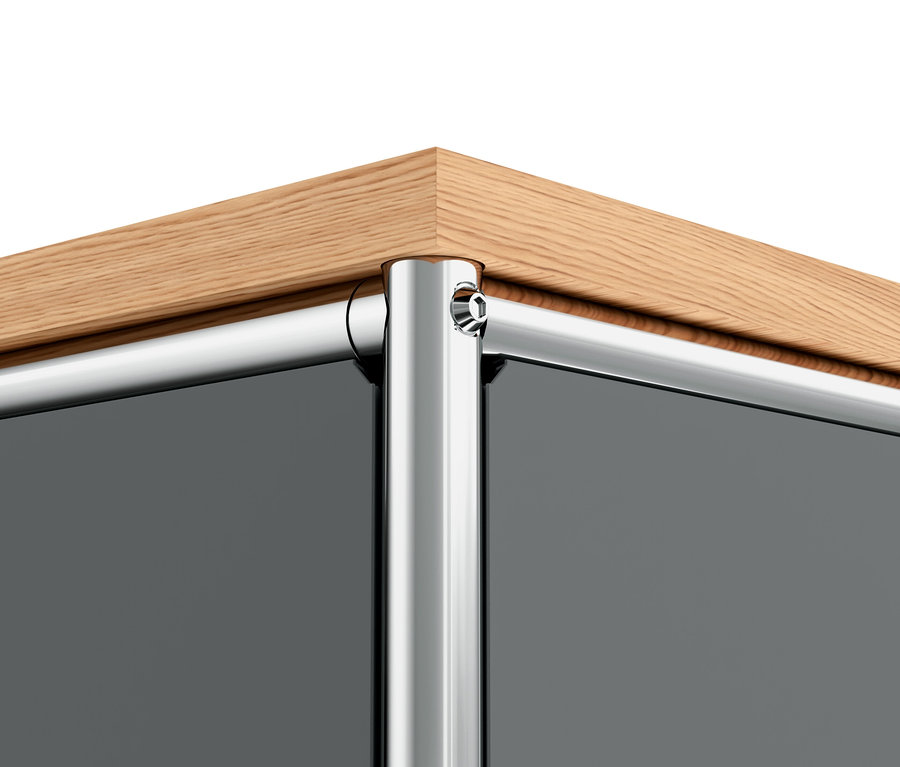 Détail du coin d'un meuble en métal gris « CN3 » avec plateau en bois.