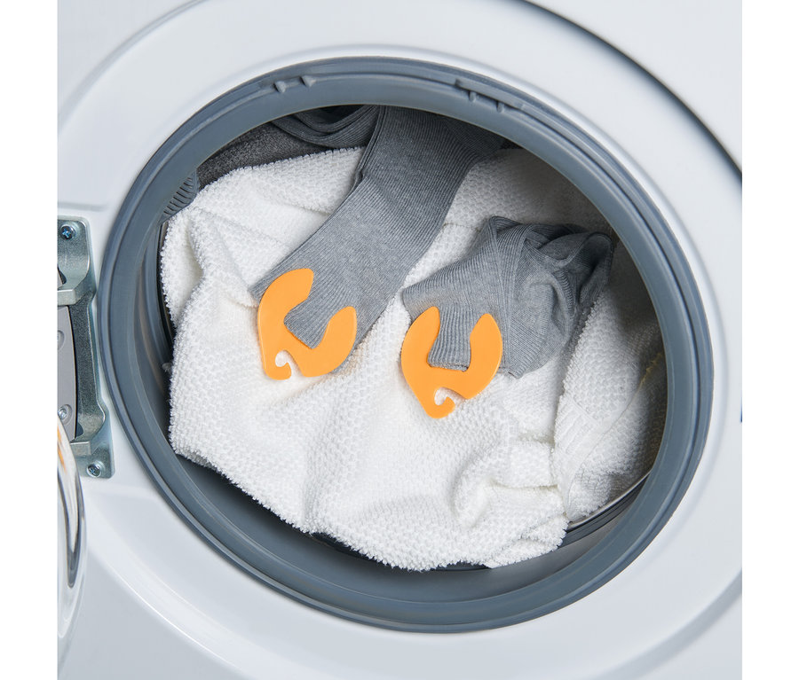 Dans un lave-linge, une serviette et deux paires de chaussettes grises sont reliées par 20 clips à chaussettes.