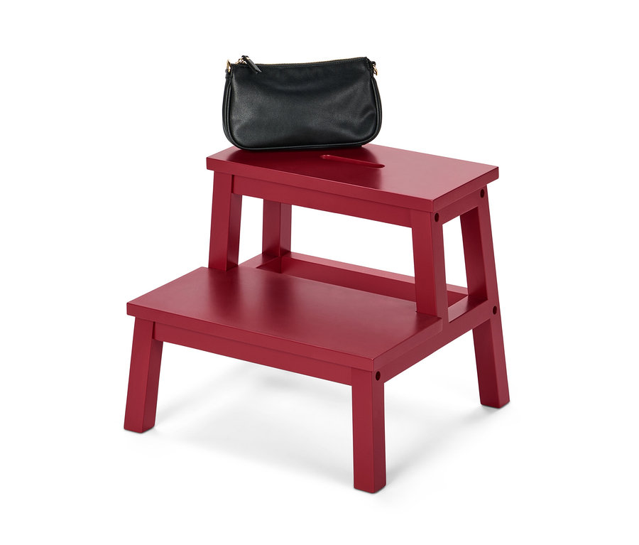 Un sac à main noir est posé sur un marchepied rouge.
