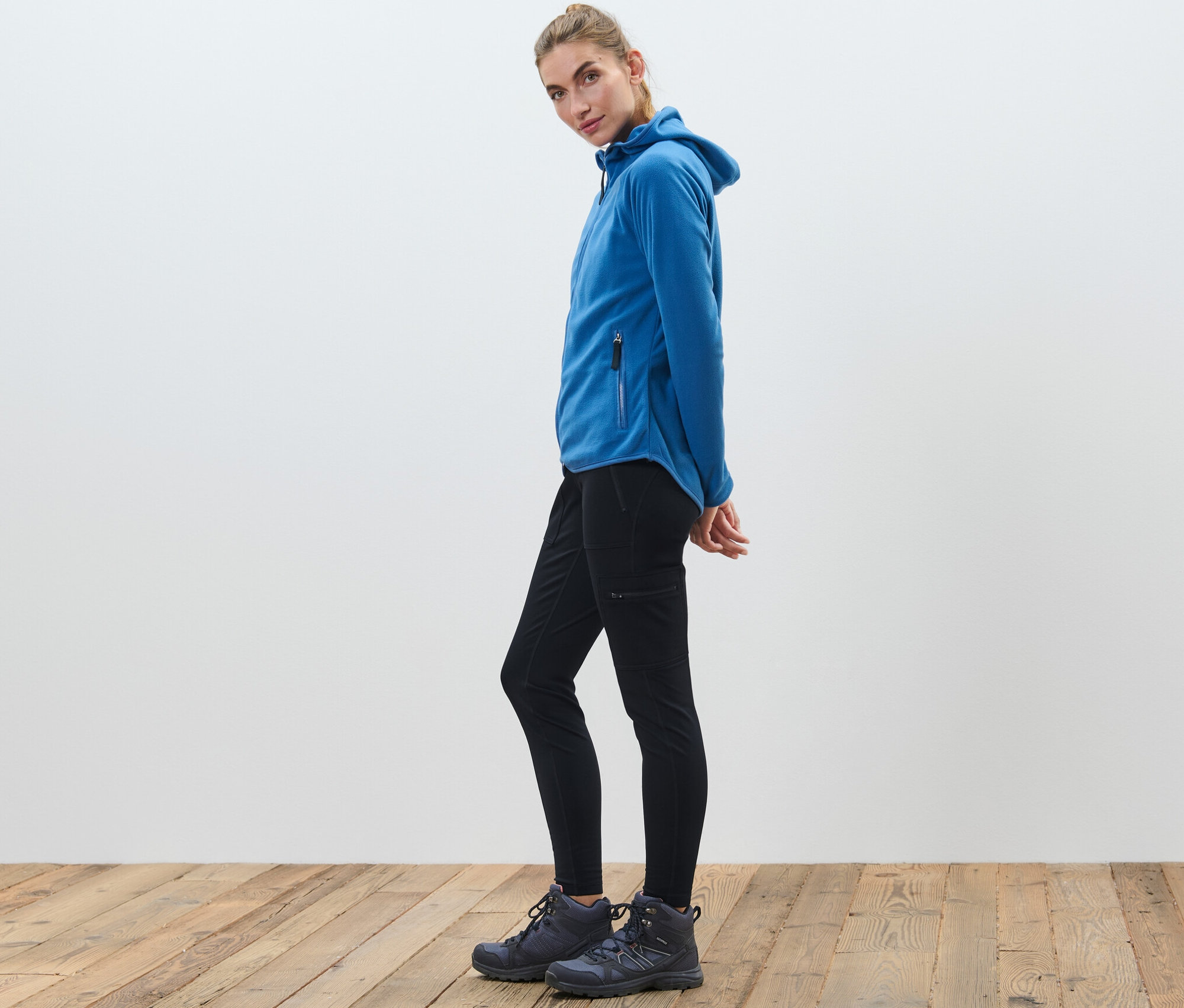 Femme portant un legging thermique outdoor et une veste polaire bleue.