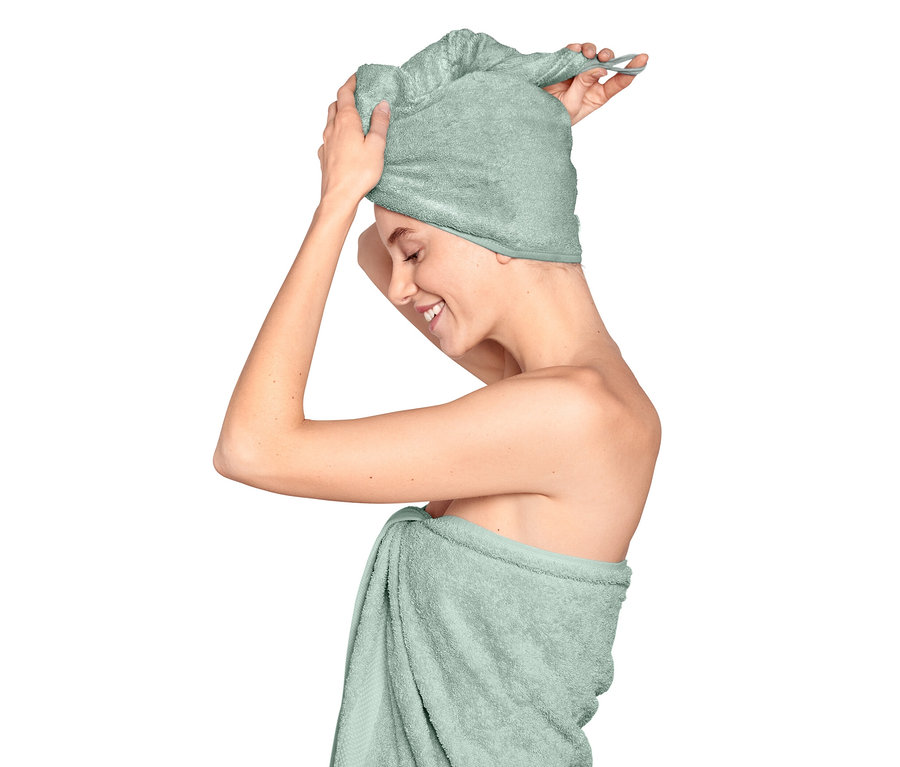 Une femme met une serviette turban bleu clair sur sa tête.