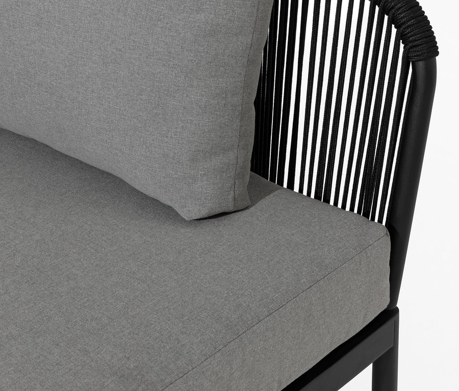 Détail d'une lounge modulaire avec tressage textile, coussins gris et cadres noirs.
