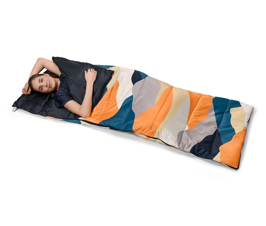 Femme allongée dans un sac de couchage 4 en 1 à motifs colorés.