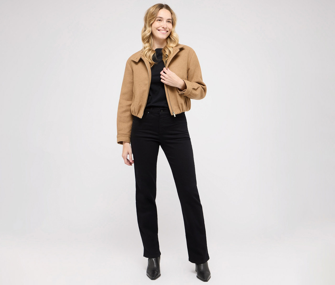 Femme posant en jean Angels Denim « Lara », coupe droite, haut noir et veste marron.